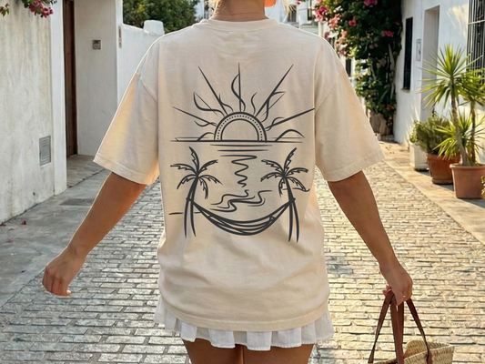 beige comfort colors t-shirt with a back graphic design of a sun, palm trees, beach and a hammock.