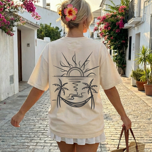 beige comfort colors t-shirt with a back graphic design of a sun, palm trees, beach and a hammock.