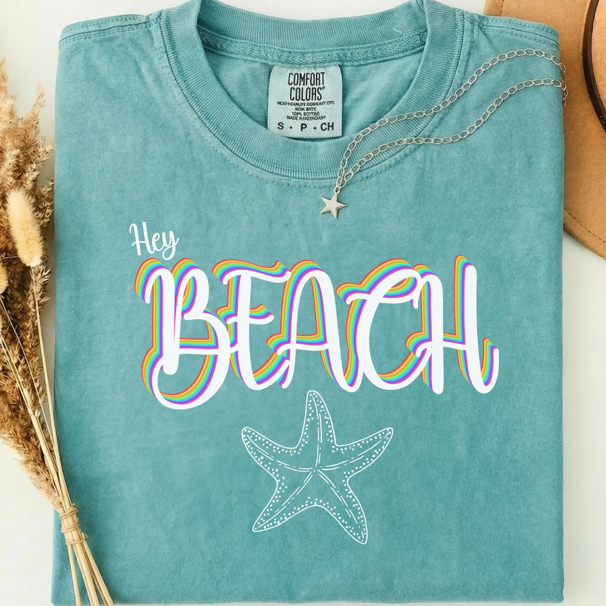 seafoam comfort colors t-shirt with a rainbow 'Hey BEACH' text and a starfish design.